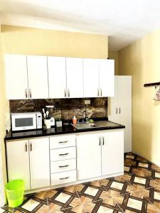 a kitchen with white cabinets and a microwave at Nicolas House #2 with Lake Atitlán View in San Pedro La Laguna