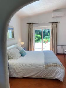 een slaapkamer met een groot bed en een groot raam bij Casa dos Arcos - Penina Villa in Portimão