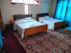 two beds in a room with blue drapes at HOTEL REGENCY in Srinagar