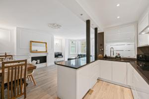 a kitchen and dining room with white cabinets and a table at Stunning 3 bed 2 bathroom BASEMENT flat in earls court, London in London