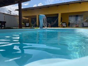 a swimming pool with a water fountain at Casa Temporada Suítes in Maragogi