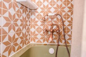 a bath tub with a shower head in a bathroom at The Old Forge, Great Glemham in Great Glemham