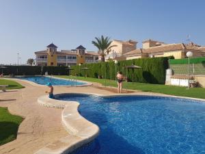 a couple of people standing around a swimming pool at Apartamento MonteGolf con TERRAZA PRIVADA in Orihuela Costa