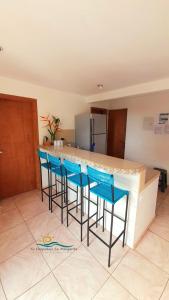 a kitchen with a bar with four blue bar stools at Posada Villa Mayo Apartamento Familiar a 5 Min de Playa Parguito in Paraguchi