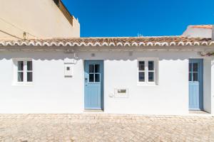 een wit gebouw met een blauwe deur en ramen bij Casa Formosa - Serena Tradição in Santa Luzia