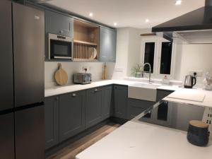 a kitchen with gray cabinets and a microwave at Great Coombe, Bookham Court in Dorchester