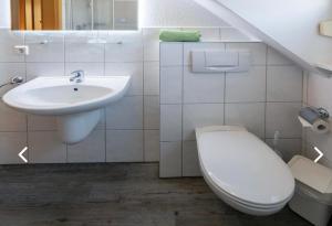 a white bathroom with a sink and a toilet at Lütten Uttied I in Norddeich +7 photos
