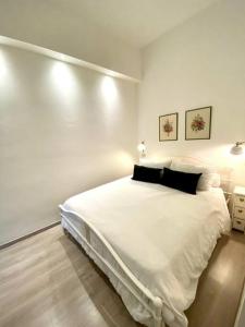 Dormitorio blanco con cama blanca grande y almohadas negras en Appartamento vicino al mare- IL GIACINTO, en Civitanova Marche