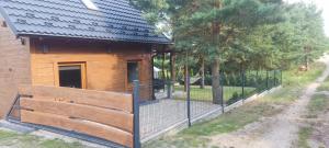 a wooden cabin with a fence in front of it at Domek Sworne Zacisze in Swornegacie 