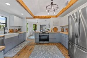 una cucina con armadi bianchi e frigorifero in acciaio inossidabile di The Pinewood House a Waco