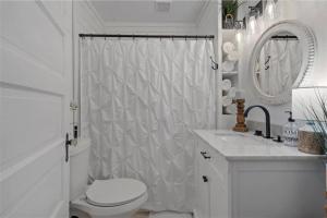 a white bathroom with a toilet and a shower at The Pinewood House in Waco