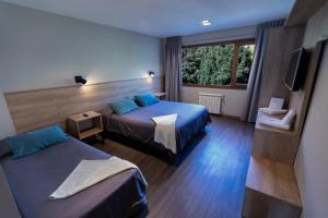 a hotel room with two beds and a window at Hotel 7 Lagos in San Carlos de Bariloche