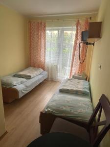 ムジェジノにあるPokoje Delfin Hostelのベッド2台と窓が備わる小さな客室です。