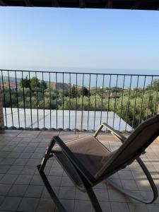 a chair on a balcony with a view of the water at DaVi' casa vacanze. Un sogno immerso nel verde ! in Montepagano