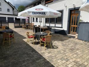 an outdoor patio with tables and chairs and an umbrella at Gasthaus Schürmann in Üdersdorf