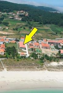 una freccia gialla che punta verso la spiaggia e gli edifici di Apartamento cerca de la playa a Finisterre