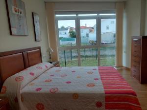 een slaapkamer met een bed en een groot raam bij Apartamento cerca de la playa in Finisterre