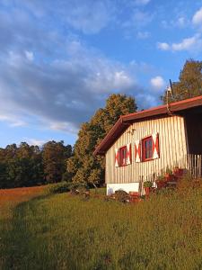 eine Holzscheune mit roten Fenstern auf einem Feld in der Unterkunft Ellernhof im Spessart in Stadtprozelten