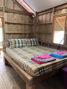 a bed in a wooden room with two pillows on it at Toh Tao Homestay 