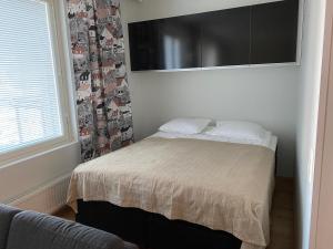 a bedroom with a bed and a window and a couch at Rauhallinen asunto, sauna ja iso parveke - raitiovaunureitin varrella in Tampere