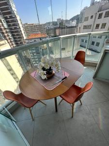 a wooden table and chairs on a balcony at Estanconfor Praia Santos AC garagem sacada fechada in Santos