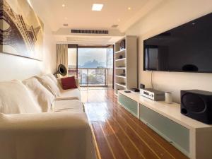 uma sala de estar com um sofá branco e uma televisão em Camarote VIP Vista Mar e Por do Sol em Ipanema A1-009 no Rio de Janeiro