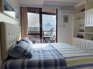 um quarto com uma cama e vista para uma varanda em Camarote VIP Vista Mar e Por do Sol em Ipanema A1-009 no Rio de Janeiro