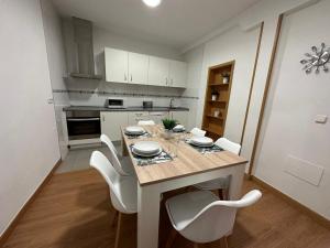 eine Küche mit einem Esstisch und weißen Stühlen in der Unterkunft Apartamento Lujo centro histórico in Valladolid
