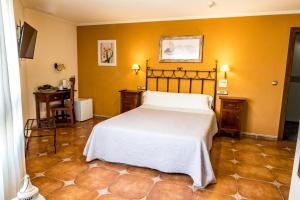 a bedroom with a large bed and yellow walls at Hostal La Posada in Torrellano
