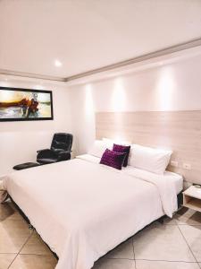 um quarto com uma grande cama branca e uma cadeira preta em Hotel Radoa em El Banco