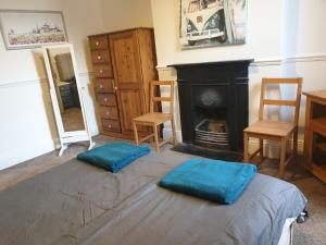 a bedroom with a bed with blue pillows in front of a fireplace at Large first floor flat walking distance to beach in Weston-super-Mare