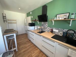 uma cozinha com armários brancos e uma parede verde em STUDIO OSAKA - HYPER CENTRE LORIENT em Lorient