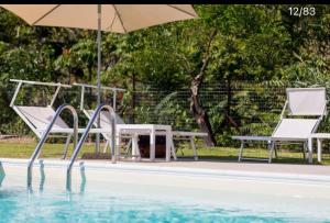 einen Pool mit 2 Stühlen, einem Tisch und einem Sonnenschirm in der Unterkunft Casa Veda elegant Rooms in Fiumefreddo di Sicilia