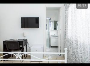 um quarto branco com uma secretária e uma televisão em Casa Veda elegant Rooms em Fiumefreddo di Sicilia