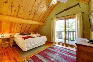 1 dormitorio con cama y ventana grande en Secluded Log Cabin in NW Michigan Fire Pit and Deck, en Evart