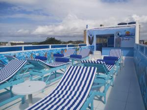 una terraza con sillas azules y blancas y una piscina en Pousada e Hotel Malibu, en Paulista