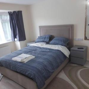 a bedroom with a bed with a blue comforter at Lovely & Beautiful 2 Bed-Apartment in Borehamwood in Borehamwood
