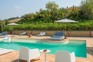 a swimming pool with chairs and umbrellas in a yard at Relais Il Margarito in Montefano