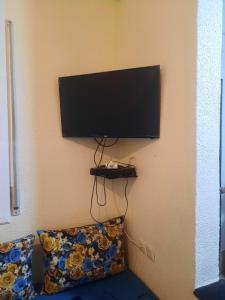 une télévision à écran plat suspendue sur un mur avec un canapé dans l'établissement Mini villa, à Saïdia