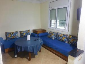 Mini villa في السعيدية: غرفة معيشة مع أريكة زرقاء وطاولة