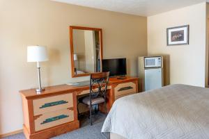 a bedroom with a desk with a bed and a mirror at Oregon Trail Inn in Buhl