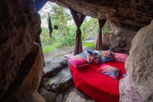 Zimmer mit einem roten Bett in einer Höhle in der Unterkunft Pousada Flor de Açucena in Igatu