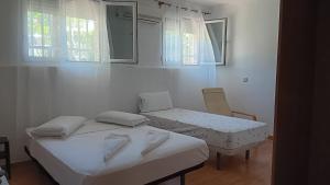 Pokój z 2 łóżkami, krzesłem i oknami w obiekcie El Colmenar Habitaciones w Madrycie