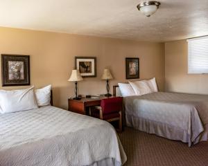 a hotel room with two beds and a desk at Oregon Trail Inn in Buhl