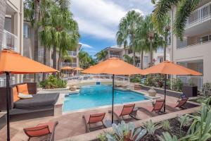 an outdoor swimming pool with chairs and umbrellas at Poolside luxury on Hastings St 212 in Noosa Heads