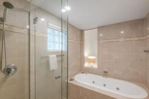a bathroom with a tub and a glass shower at Poolside luxury on Hastings St 212 in Noosa Heads +7 photos