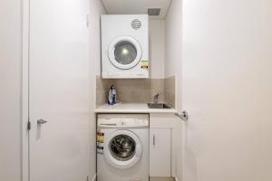 a laundry room with a washing machine and a sink at Poolside luxury on Hastings St 212 in Noosa Heads