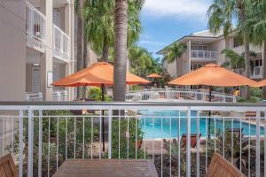 a balcony with orange umbrellas and a swimming pool at Poolside luxury on Hastings St 212 in Noosa Heads