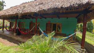 a green house with a hammock in front of it at El Retiro Lanquin in Lanquín