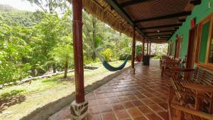 eine Veranda mit Bänken und einer Hängematte auf einem Haus in der Unterkunft El Retiro Lanquin in Lanquín